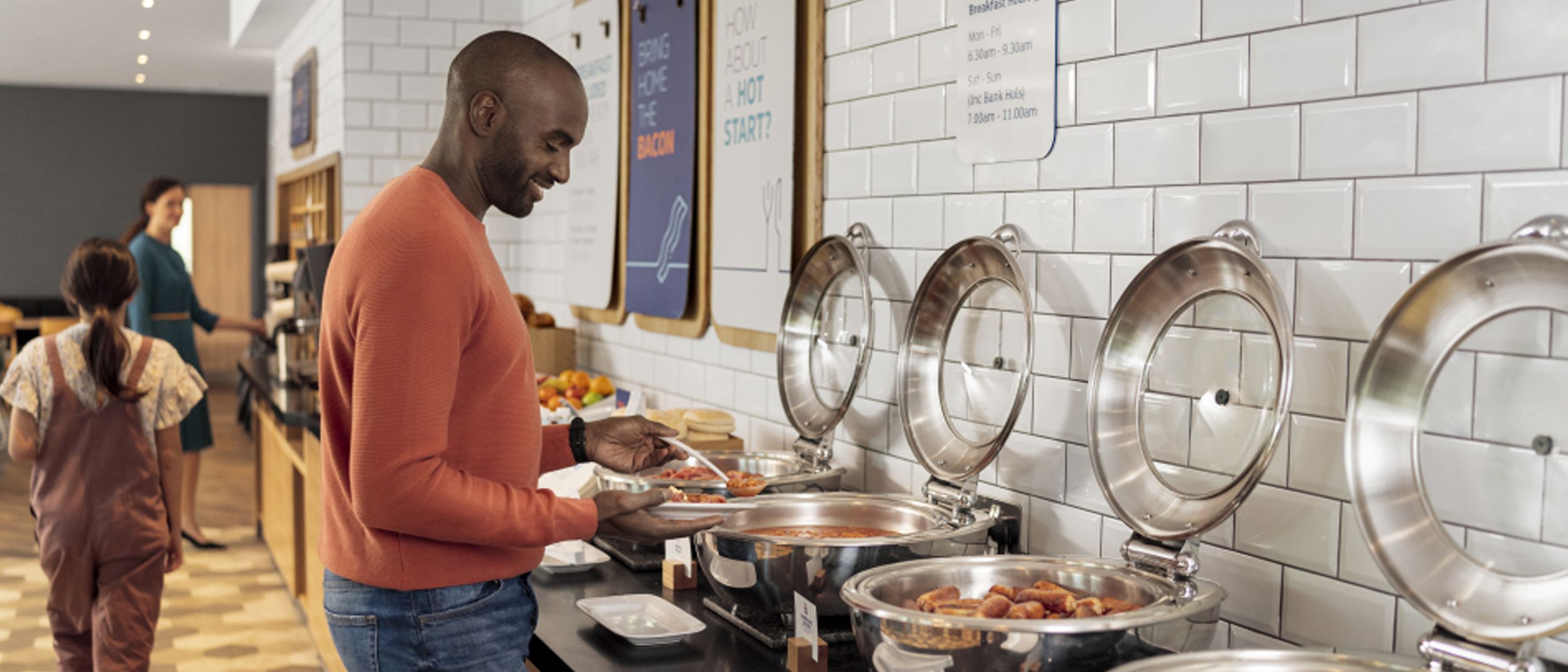 A man smiling while serving food from a hot buffet at Holiday Inn Express